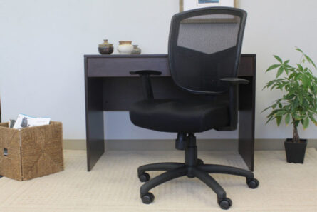 Office setup with a Contract Mesh Task Chair at a wooden desk, flanked by a small potted plant and a wicker basket with papers.