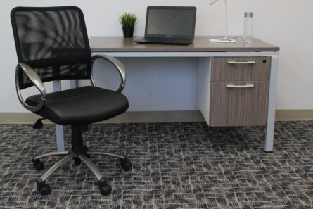 A modern office setup featuring a Mesh Back W/ Pewter Finish Task Chair, a desk with a laptop and a lamp, and a small potted plant in a bright room.