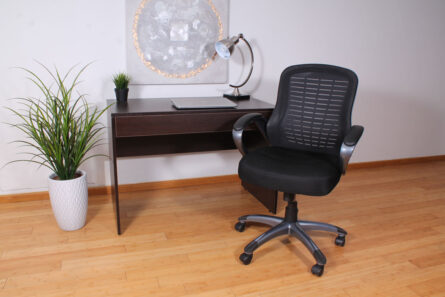 A home office setup with a Ribbed High Back Mesh Chair, a wooden desk holding a laptop, a lamp, and a decorative round mirror on the wall.