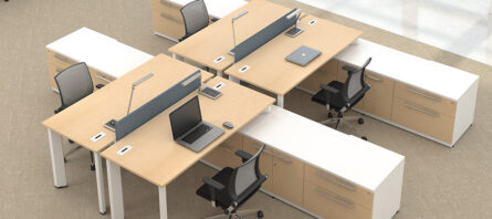 Modern office setup with four cubicles arranged in a cluster, each desk equipped with a laptop, black office chair, and privacy panels.