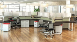 Modern office space with Novo Series desks, ergonomic chairs, and partitioned workstations, set in a room with wooden floors and large windows.