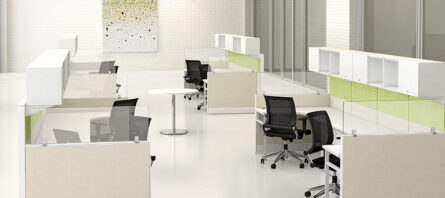 Modern office space with Interra Series desks, black chairs, green partition panels, and white tiled floor.