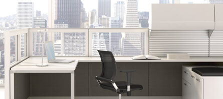 Modern office space featuring an Interra Series chair facing a desk with a computer monitor, situated against a large window overlooking a city skyline.