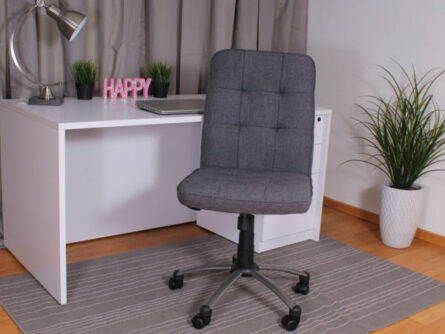 A modern home office with a Modern Office Chair-Slate Grey, white desk featuring a laptop and a 'happy' sign, and a green potted plant, set against gray curtains.