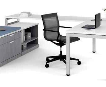 Modern office setup with an Elements Series U-shaped desk without hutch, rolling chair, desktop computer, and a potted plant on a cabinet.