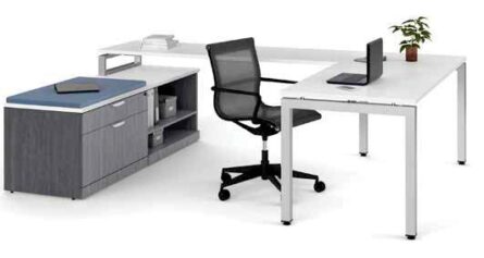 Modern office setup with an Elements Series U-shaped desk without hutch, rolling chair, desktop computer, and a potted plant on a cabinet.