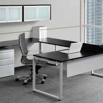 Modern office setup featuring a sleek Elements U shaped desk with a laptop, rolling chair, filing cabinet, and shelves, by a large window overlooking skyscrapers.