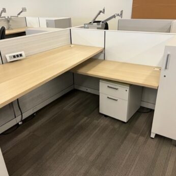 A modern office setup with empty cubicles featuring Allsteel desks, white partitions, and a mobile filing cabinet.