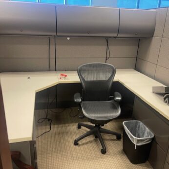 Empty office cubicle with desk and chair.