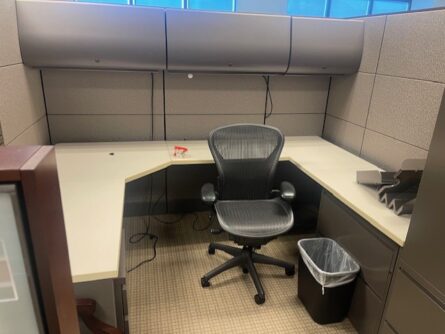 Empty office cubicle with desk and chair.