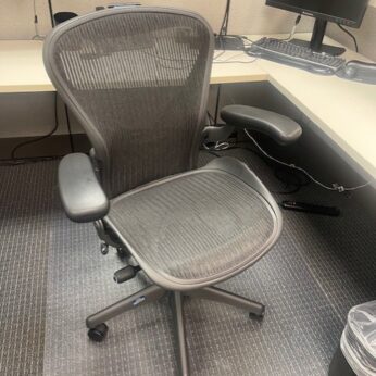 Gray mesh office chair with a clear mat.