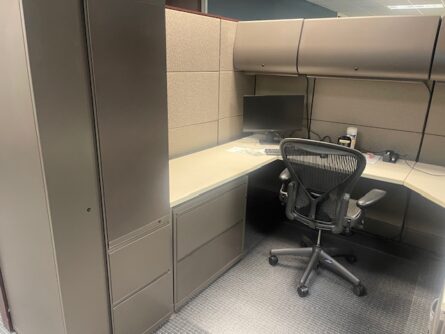 Office cubicle with desk, chair, and filing cabinet.