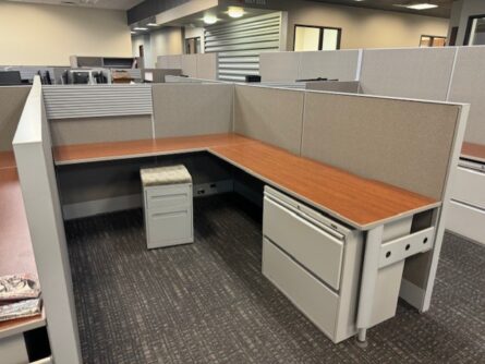 Modern office cubicle with desk and storage.